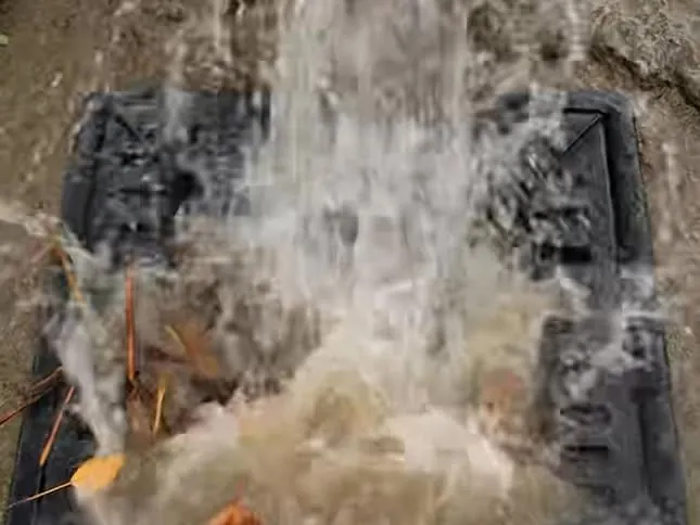 Water rushing out of a pipe and into a yard gully during drain clearing work