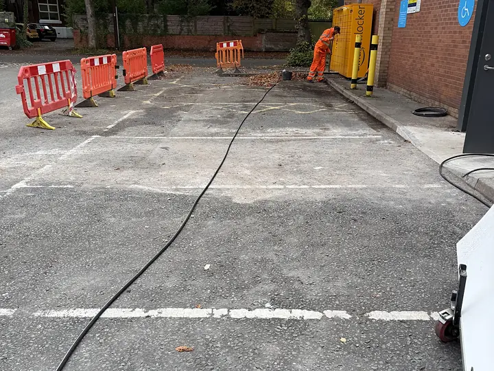 A commercial car park being jet washed, with the work area barriered off